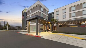 Een modern hotel met een overdekte ingang, een vlag en een goed verlicht buitengebied.