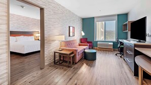 Een moderne hotelkamer met een bed, een sofa, een bureau en een televisie.