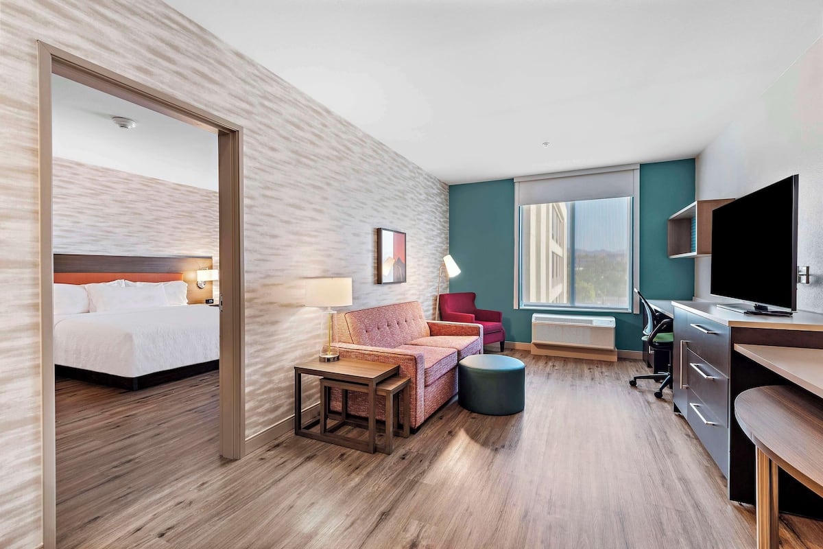 Een moderne hotelkamer met een bed, een sofa, een bureau en een televisie.