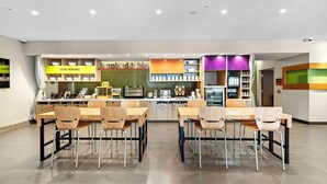 Een modern café met een centraal eiland, houten tafels en stoelen.