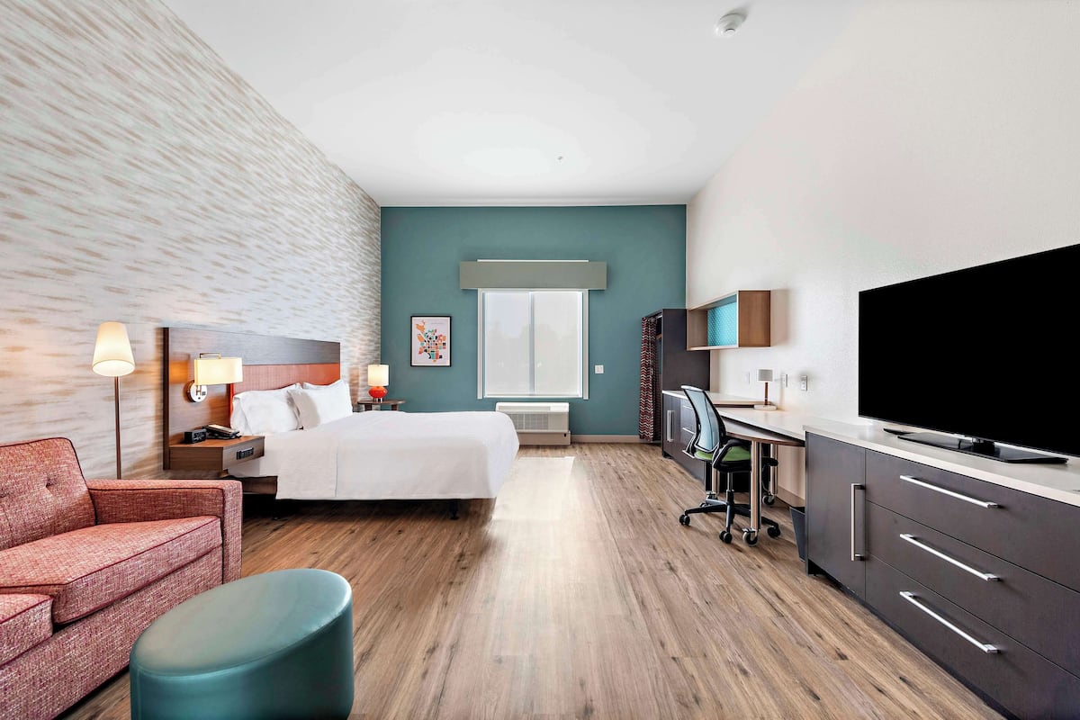 Een hotelkamer met een bed, een bureau, een televisie, een bank en een stoel.