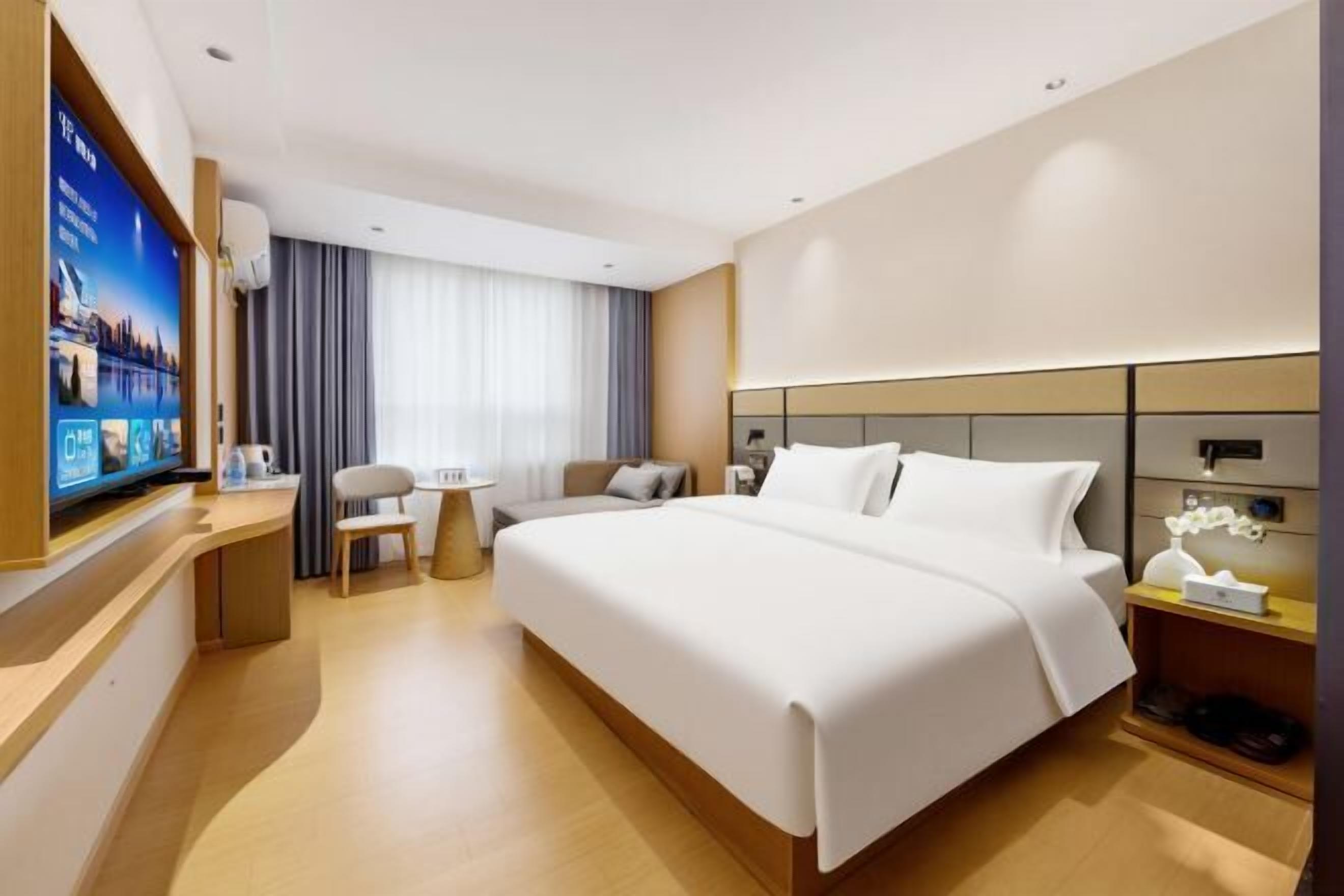 A hotel room with a large bed, a desk, a television, and a small table.