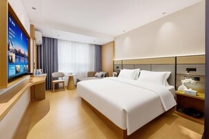 Habitación de hotel con una cama grande, un escritorio, un televisor y una mesita.