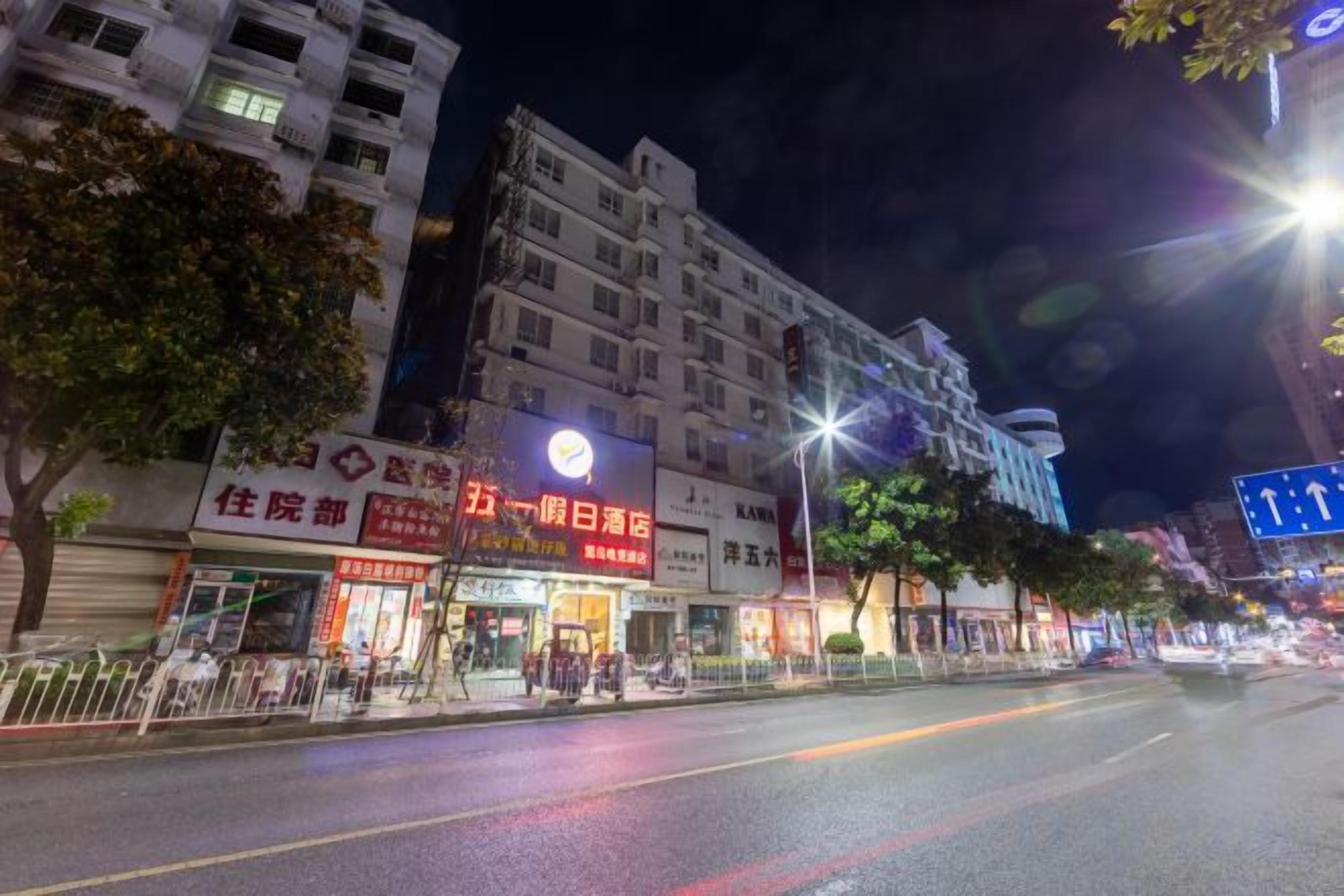 Vista de carrer de nit amb botigues il·luminades, incloent un hotel i un restaurant.