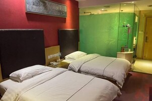 A hotel room with two beds, a green accent wall, and a wooden wardrobe.