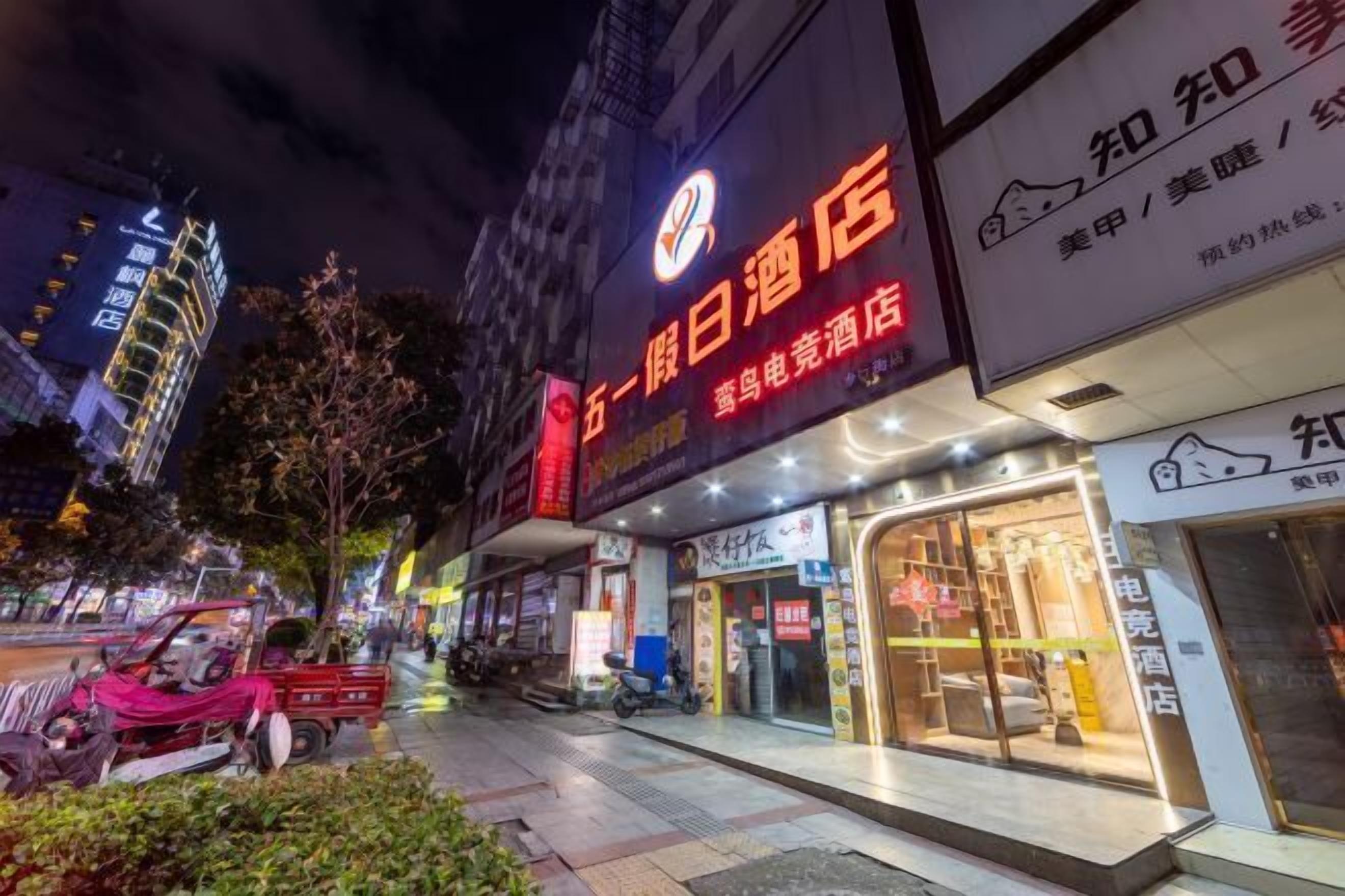 A hotel with illuminated signage, a visible entrance, and a sidewalk in front.