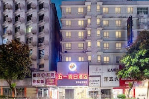 Un edificio de varios pisos con señalización iluminada, incluyendo un letrero rojo llamativo con texto blanco y un logotipo.