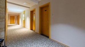 A hotel corridor with doors, a patterned floor, and a plain wall. - Wuyi E-Sports Hotel (Chenzhou)