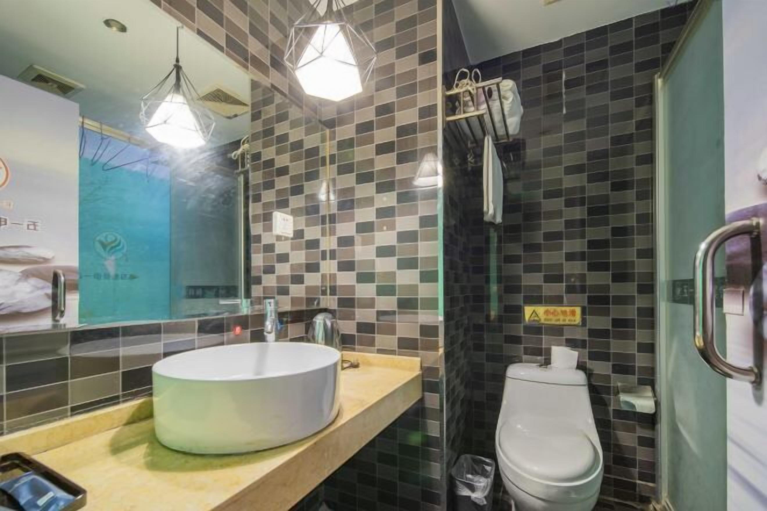 A bathroom with a round sink, a toilet, and a glass shower enclosure.