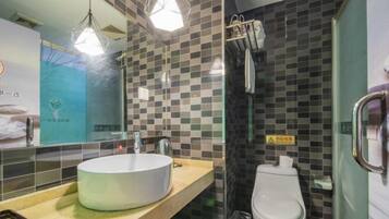 A bathroom with a round sink, a toilet, and a glass shower enclosure.