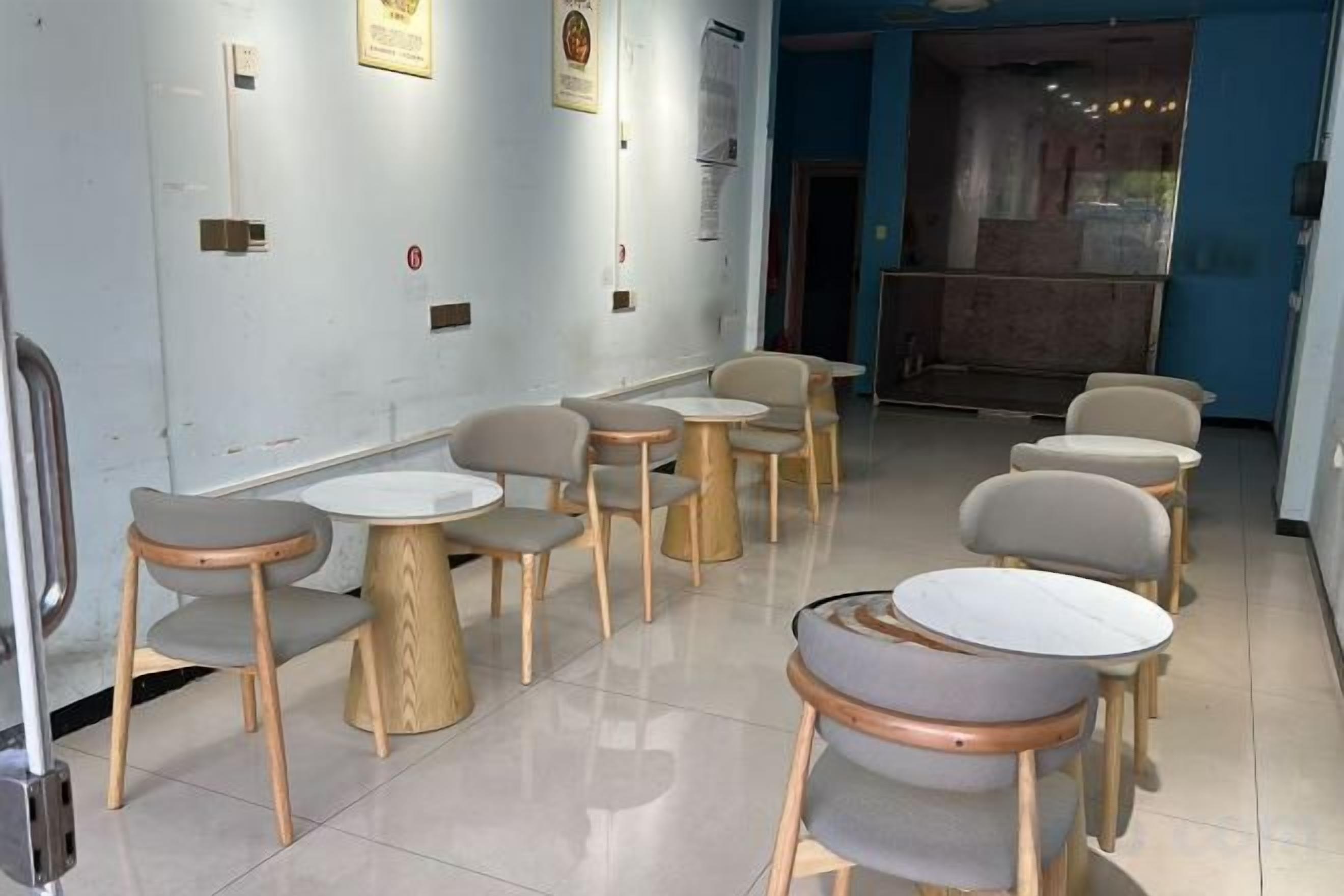A seating area with round tables and chairs, a tiled floor, and a blue wall with a door in the background.