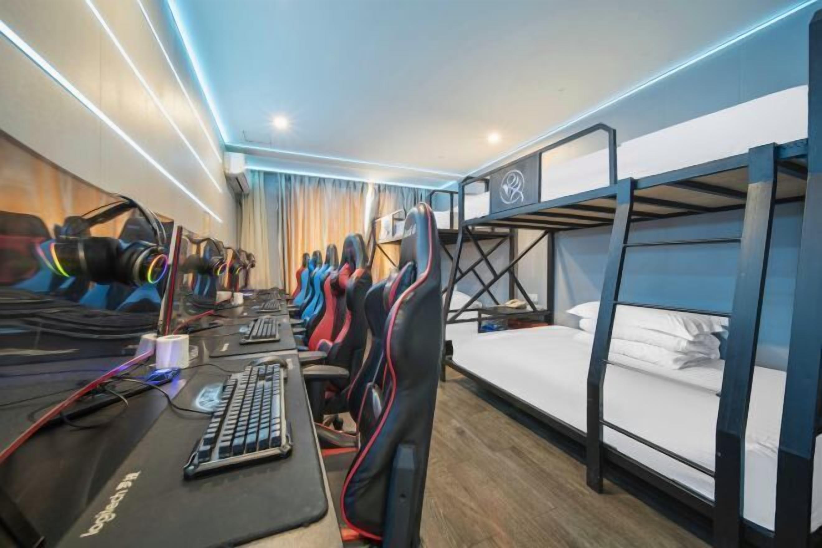 Una sala de juegos con varias sillas gamer, un escritorio con computadora y literas.