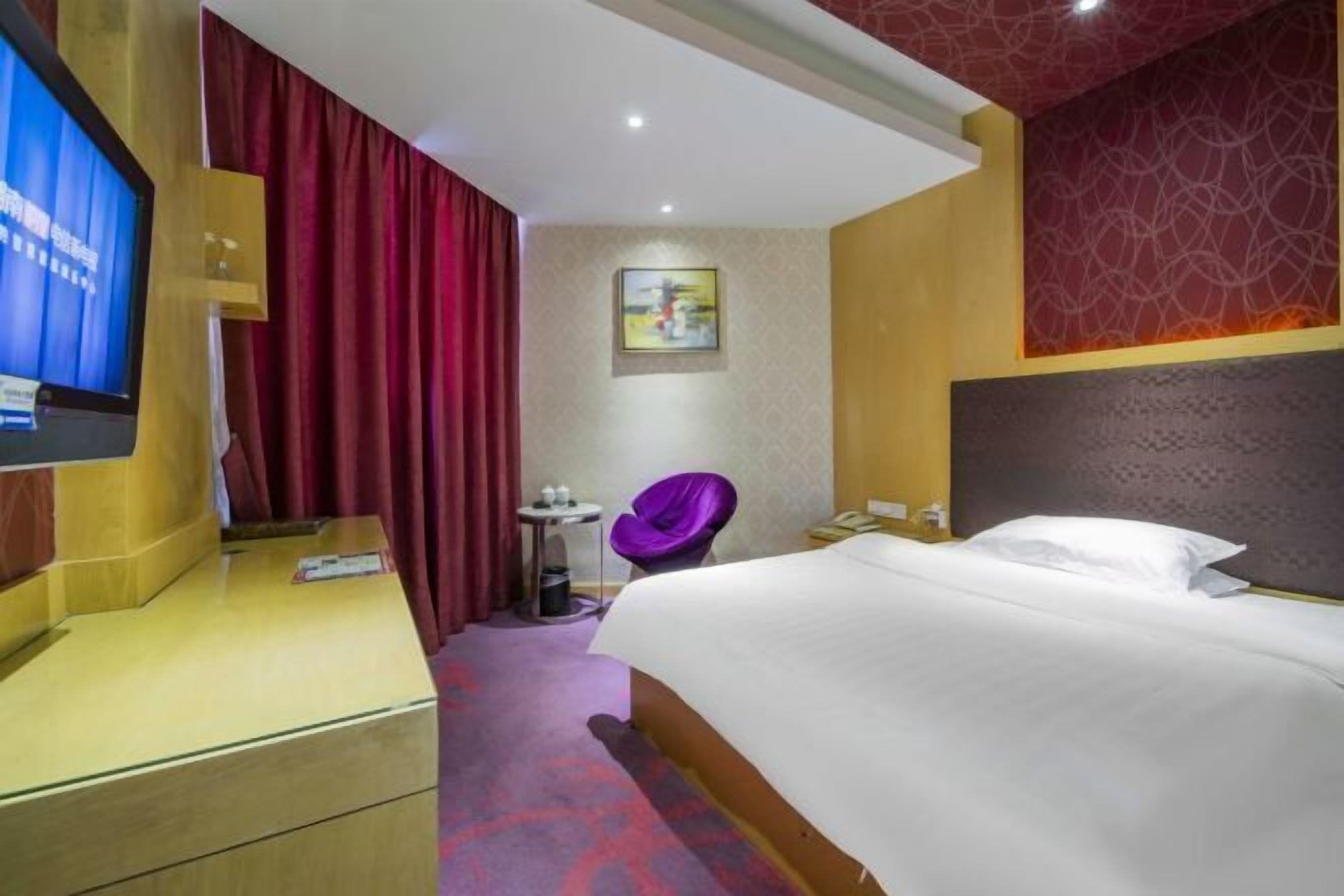 A hotel room with a bed, a TV, a desk, a chair, and a small table.