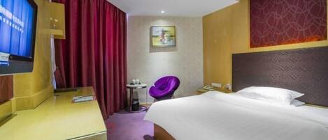 A hotel room with a bed, a TV, a desk, a chair, and a small table.