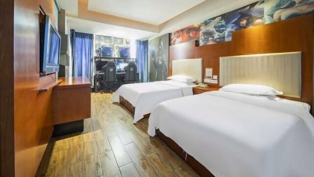 A hotel room with two beds, a desk, a TV, and artwork on the walls. - Wuyi E-Sports Hotel (Chenzhou)