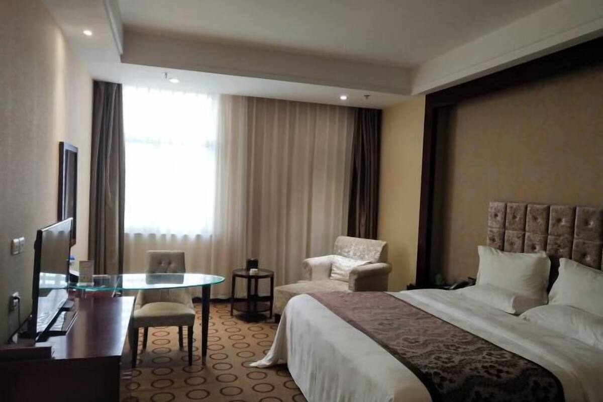 Une chambre d’hôtel avec un grand lit, un bureau avec un ordinateur, une chaise et une petite table.