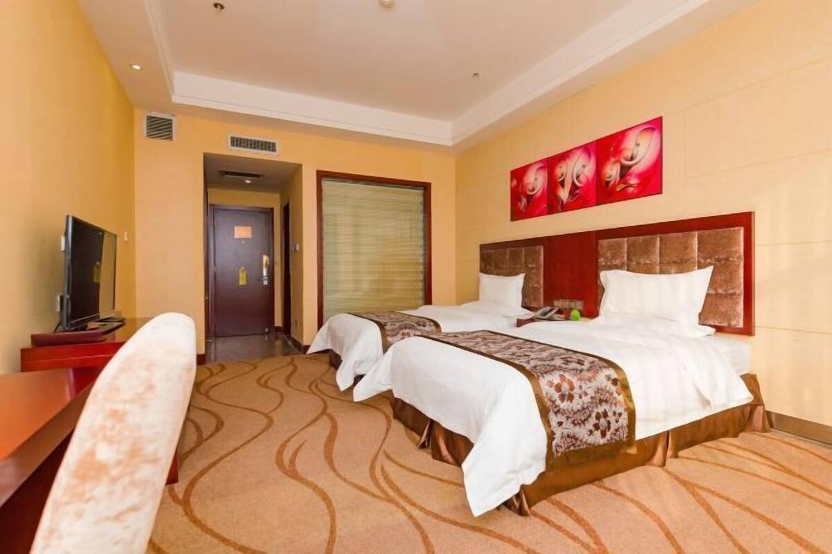 Une chambre d’hôtel avec deux lits, une télévision et un bureau.