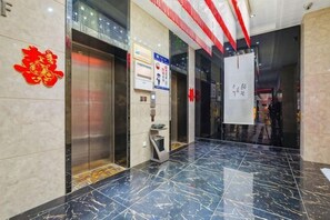 A hotel lobby with marble flooring, elevators, and a reception area. - Longfengxiang Hotel (Dongying)