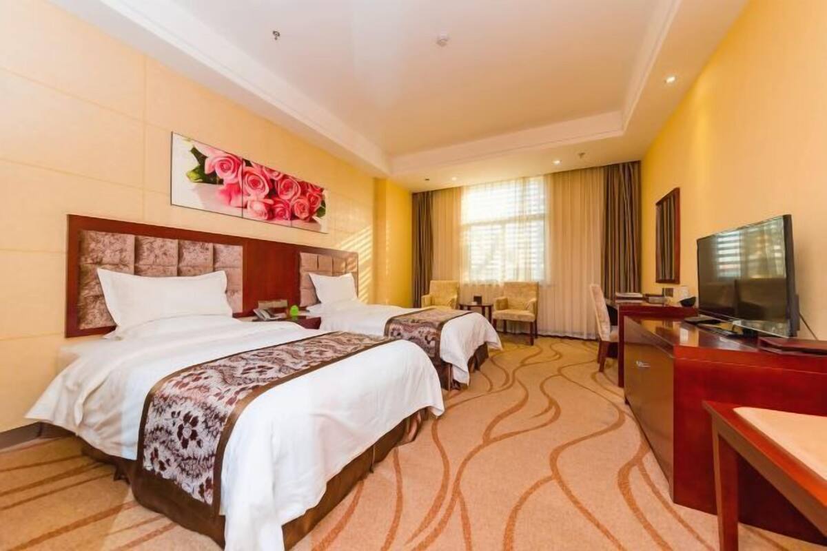 Une chambre d’hôtel avec deux lits, une télévision, un bureau et une chaise.