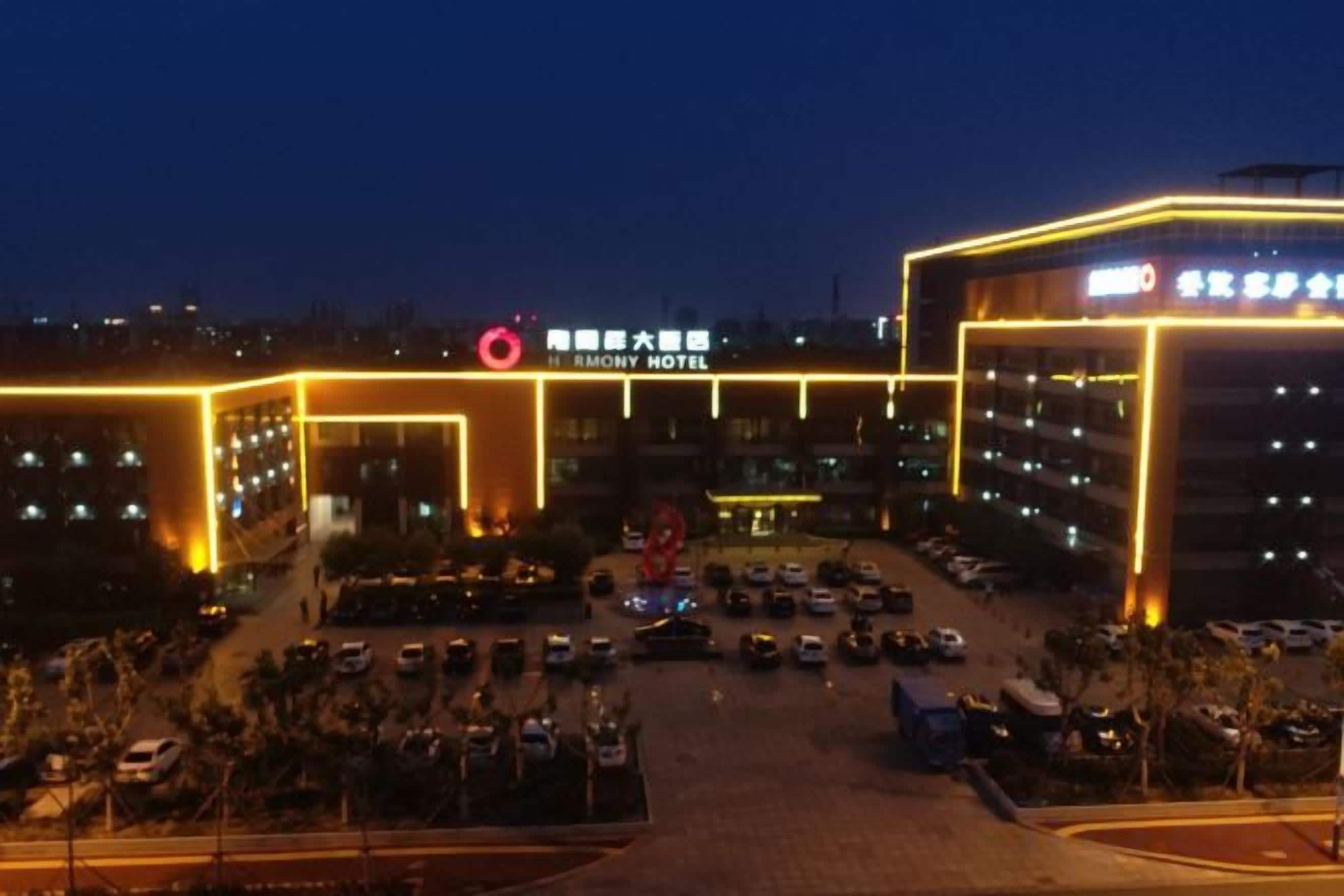 A multi-story hotel with a prominent sign, a parking lot, and a well-lit entrance.