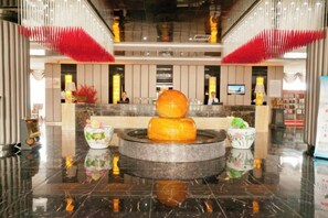 A hotel lobby with a reception desk, a decorative fountain, and a polished marble floor. - Longfengxiang Hotel (Dongying)
