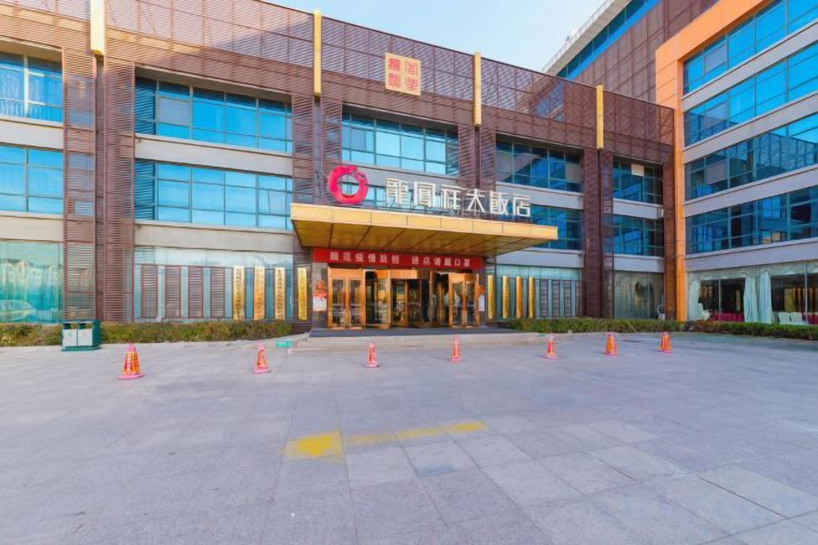 A modern building with a prominent entrance, large windows, and a clear sky.