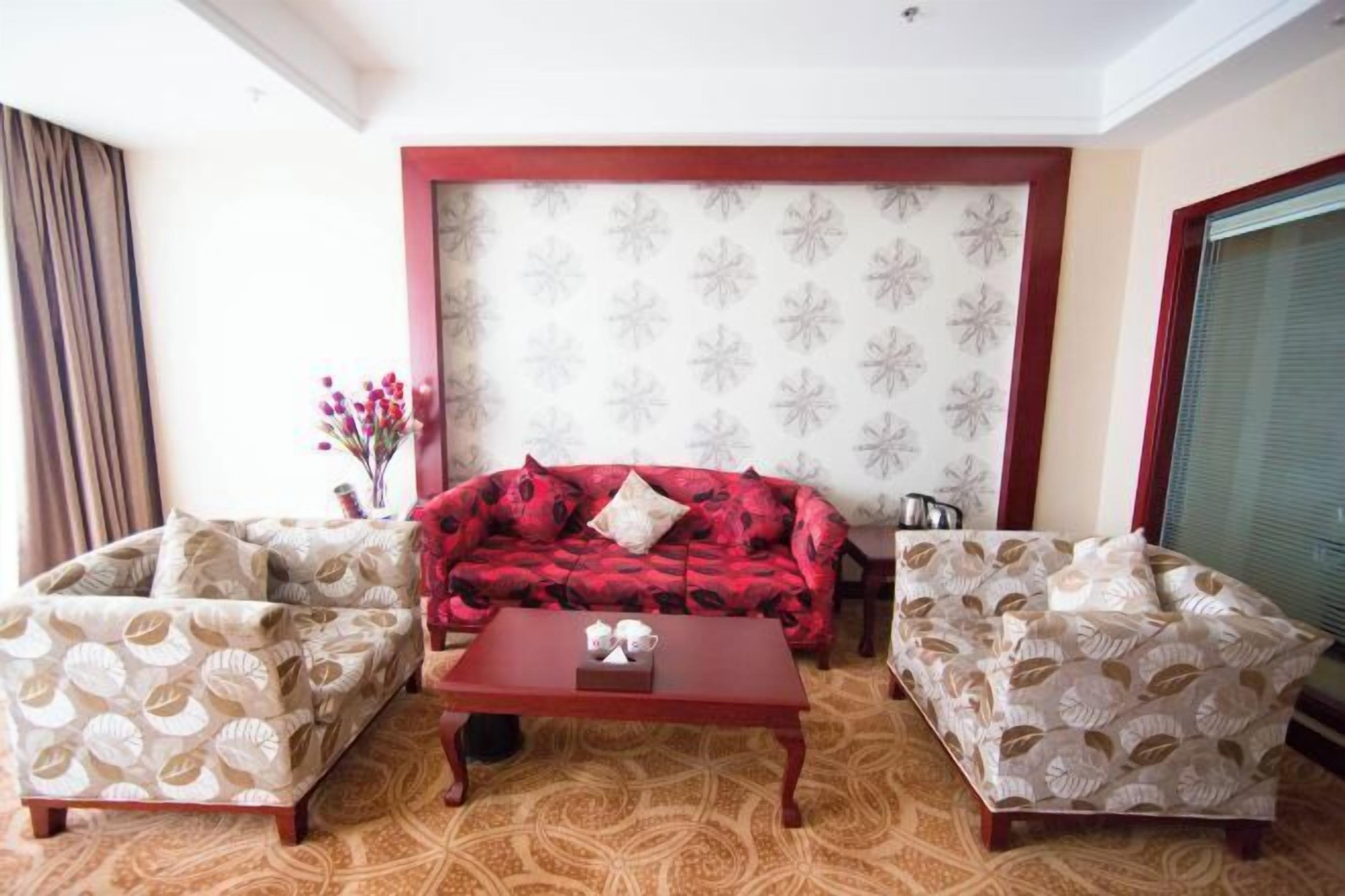 A living room with a red sofa, two patterned armchairs, and a wooden coffee table.