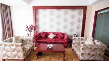 A living room with a red sofa, two patterned armchairs, and a wooden coffee table.