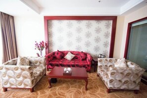 A living room with a red sofa, two patterned armchairs, and a wooden coffee table. - Longfengxiang Hotel (Dongying)