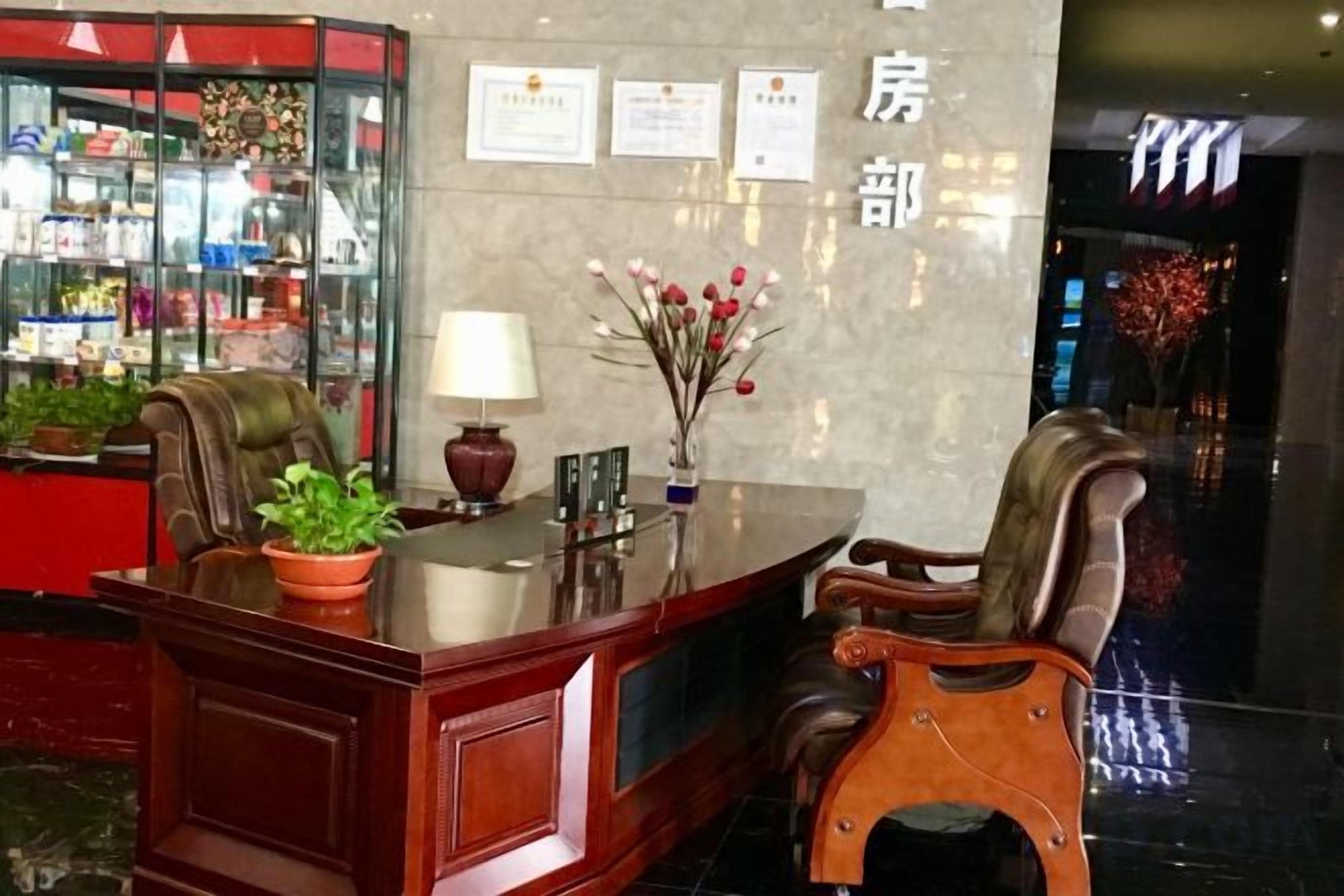 A reception desk with a plant, a lamp, and certificates on the wall.