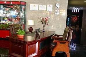A reception desk with a plant, a lamp, and certificates on the wall. - Longfengxiang Hotel (Dongying)