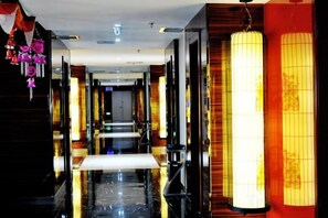 A hotel corridor with a reflective floor, a central walkway, and traditional-style lanterns on the walls. - Longfengxiang Hotel (Dongying)