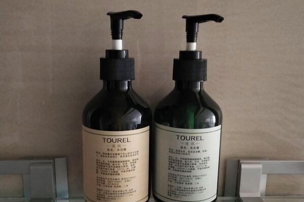 Two bottles of Tourel skincare product on a shelf. - Longfengxiang Hotel (Dongying)