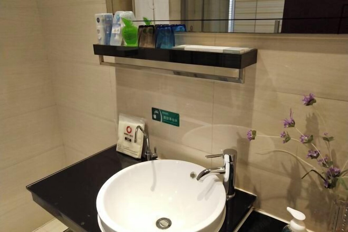 A bathroom with a white sink, a mirror, and a shelf with toiletries.