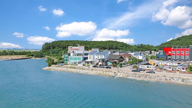 A coastal town with a mix of modern and traditional buildings, a marina, and a bridge in the distance. - Daebudo Dekapo Pension (Ansan)