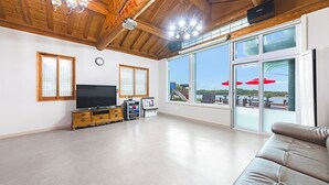 A spacious living room with a large TV, wooden cabinets, and a sofa. - Daebudo Dekapo Pension (Ansan)