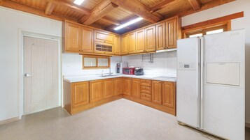 Una cocina con armarios de madera, un refrigerador blanco, un microondas y un tostador.