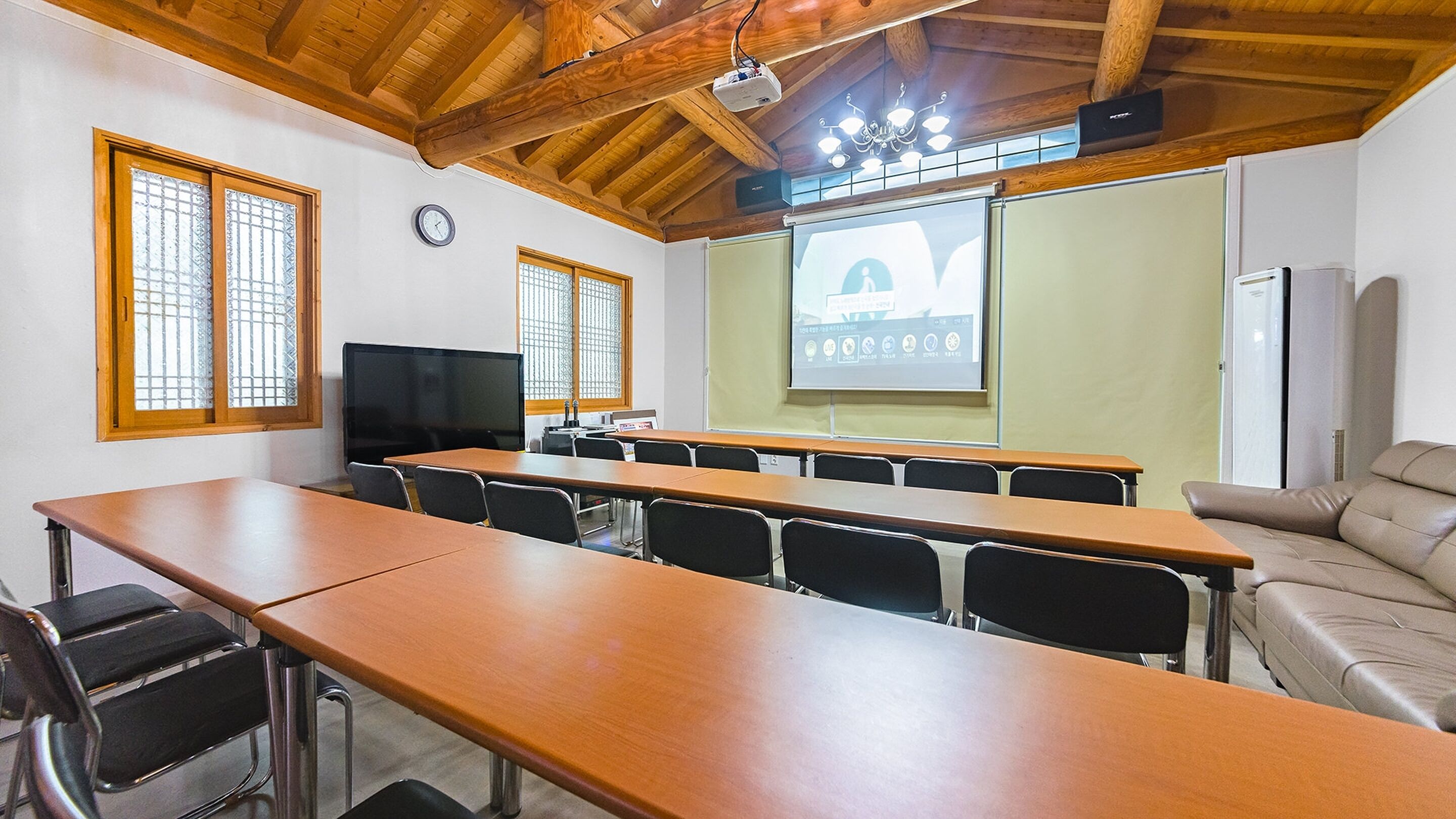 Una sala de conferencias con una larga mesa, sillas, una pantalla de proyector y una pizarra.