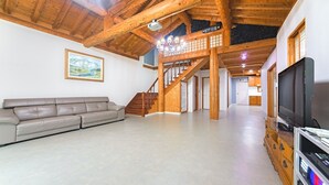 A spacious living room with a wooden staircase, a large television, and a sofa. - Daebudo Dekapo Pension (Ansan)
