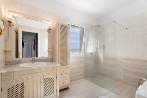 Features a large sink, spacious vanity, and glass-enclosed shower with a clear door.