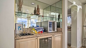 A kitchen with granite countertops, a stainless steel microwave, and a glass backsplash. - Sunny, great views, upstairs villa (Cathedral City)