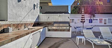 An outdoor patio with a grill, seating area, and a pool with lounge chairs.