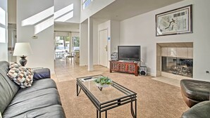 A spacious living room with a leather sofa, a glass coffee table, a fireplace, and a television. - Sunny, great views, upstairs villa (Cathedral City)