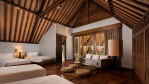 A spacious room with wooden beams on the ceiling, two beds, a sofa, and a large window with curtains. - Villa Tirtadari by Nakula (Kerobokan)