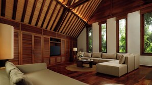 A spacious living room with a wooden ceiling, a large sofa, a coffee table, and a television. - Villa Tirtadari by Nakula (Kerobokan)