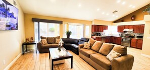 A spacious living room with a brown leather sofa, a coffee table, and a TV mounted on the wall. - Private Vegas Villa with Pool & Spa Perfect for a European Escape (North Las Vegas)