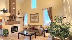 A spacious living room with a fireplace, a sofa, a coffee table, and a large potted plant. - Private Vegas Villa with Pool & Spa Perfect for a European Escape (North Las Vegas)
