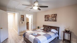 A bedroom with a bed, a ceiling fan, a painting, and a small table with a vase. - Private Vegas Villa with Pool & Spa Perfect for a European Escape (North Las Vegas)