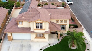 A two-story house with a garage, a well-maintained lawn, and a palm tree. - Private Vegas Villa with Pool & Spa Perfect for a European Escape (North Las Vegas)