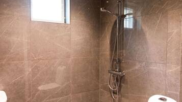 Un baño moderno con ducha, paredes de mármol y ventana.